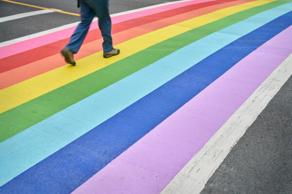 A pedestrian using the rainbow colored crosswalk in downtown Vancouver.